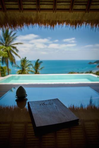 a pool with a table and a view of the ocean at Phandara Luxury Pool Villas in Koh Tao