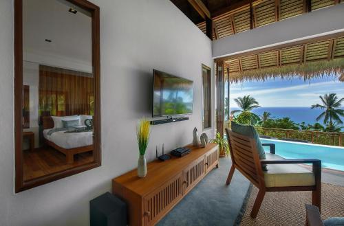 a living room with a tv and a bed and a mirror at Phandara Luxury Pool Villas in Koh Tao