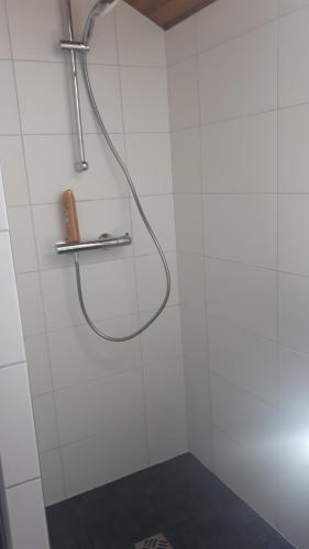 une douche avec un tuyau sur un mur carrelé blanc dans l'établissement Chalet coocooning, à Marlens