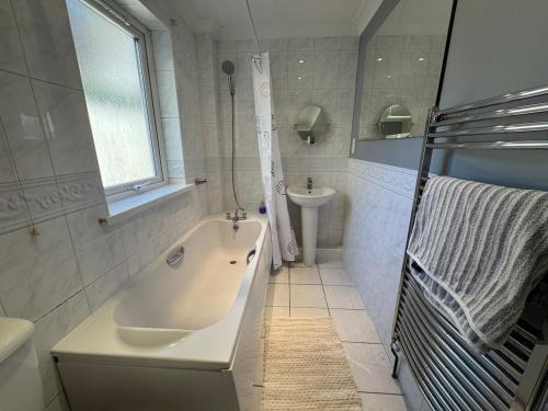 a white bathroom with a tub and a sink at Comfortable, London 1 Bed Garden in London