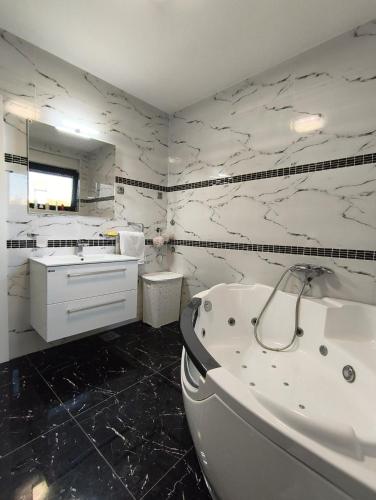 a white bathroom with a tub and a sink at Agava Club in Sremska Kamenica