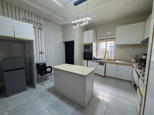 Una cocina con gabinetes blancos y una encimera blanca. en Effixzzy villa, en Lekki