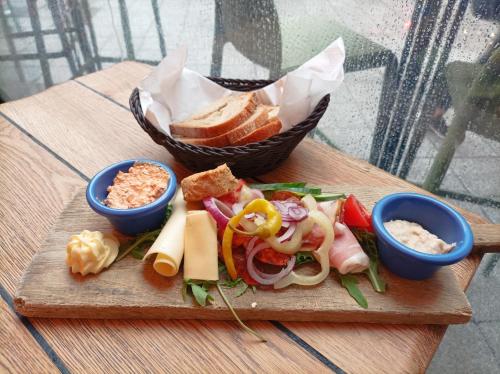 布达佩斯Mango Apartments的一块砧板上放着一个三明治，旁边还有一篮面包。