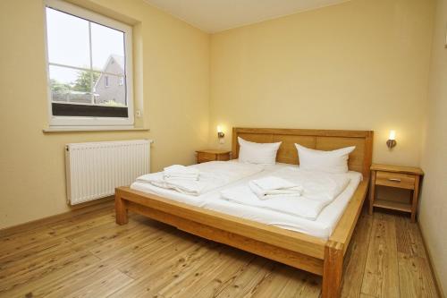 ein Schlafzimmer mit einem Bett mit weißen Laken und einem Fenster in der Unterkunft Schicke FeWo mit Terrasse, gratis Nutzung vom AHOI Erlebnisbad und Sauna in Sellin - Haus De niege Wech FeWo 01 in Thiessow