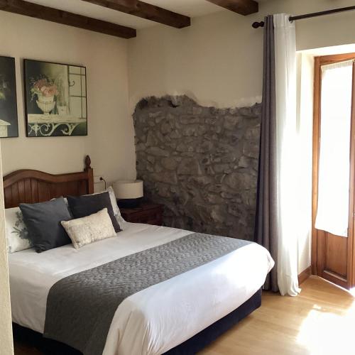 a bedroom with a bed and a stone wall at Hotel Rural Eseverry-Bosque Irati in Jaurrieta