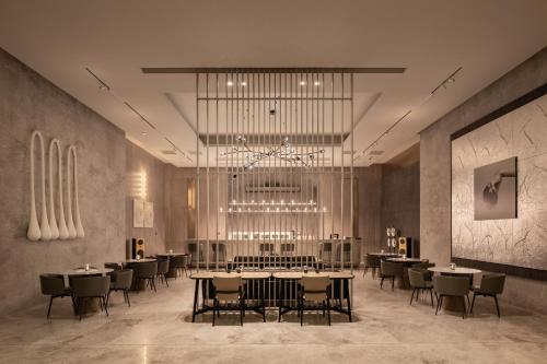 a dining room with tables and chairs and a chandelier at My Ōtel North Coast - Adult Only in Al Dabaa