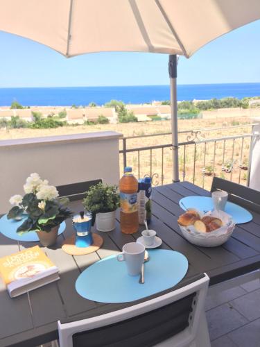 a table with food and drinks on a balcony with the beach at Casa Oltremare UnmarediBlu in San Vito lo Capo