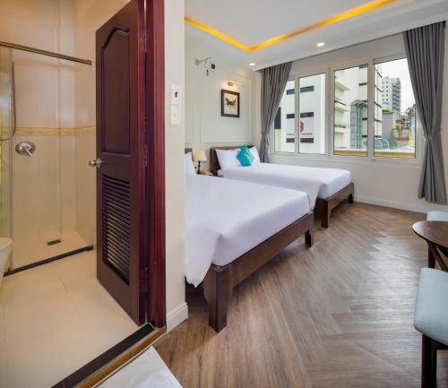a hotel room with two beds and a shower at SCAT Hotel- New World Bến Thành in Ho Chi Minh City