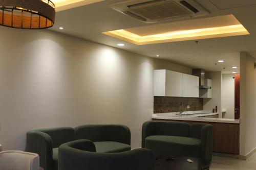 a living room with two chairs and a kitchen at Luxury Apartments at Goldcrest Mall and Residency DHA Phase 4 by Nirvana Nests in Lahore