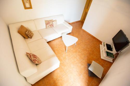 a living room with a white couch and a television at Les Villas de Perret in Joyeuse