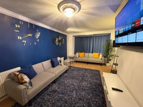 a living room with a couch and a clock on the wall at Modern & Spacious 3BR House Bracknell - Berkshire in Easthampstead