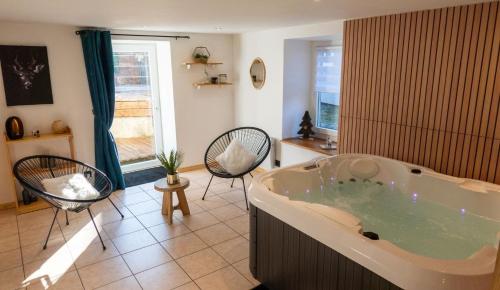 un ampio bagno con vasca, sedie e finestra di Perce Neige Bien être a La Bresse