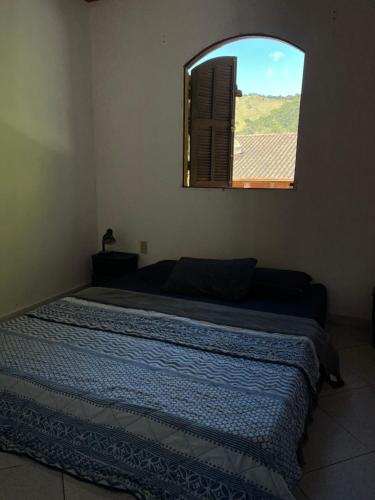 a bedroom with a large bed with a window at Casa no sana in Macaé