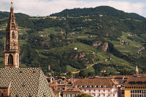 a view of a city with a clock tower and mountains at Falkensteiner Hotel Bozen WaltherPark in Bolzano