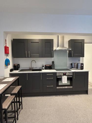 a kitchen with black cabinets and a sink at Flat 2 in Hollinwood
