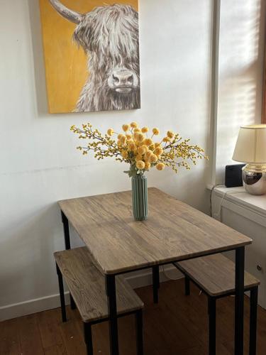 a wooden table with a vase of flowers on it at Towerwell in Newburgh