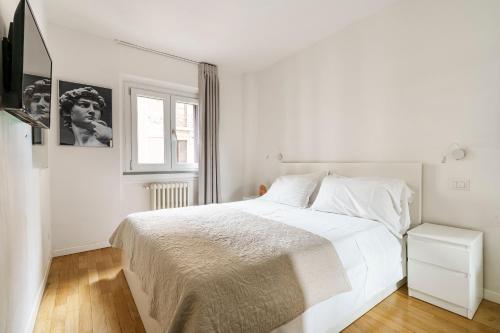 a white bedroom with a white bed and a window at CDT Duomo in Florence
