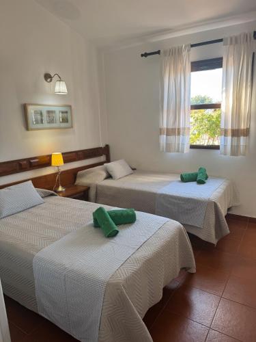 Habitación con 3 camas y toallas verdes. en Los Porches k29, en Playa del Inglés