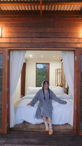 a woman sitting on a bed in a bedroom at West Mount Cafe & Restaurant in Ban Hua Hin