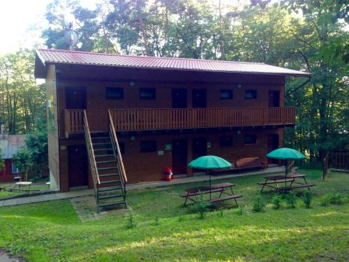 a house with two picnic tables and two green umbrellas at Lesní Penzion Vranov in Vranov nad Dyjí