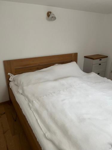 a bed with white sheets and a wooden headboard at Rufus' Bergblick in Bernau am Chiemsee