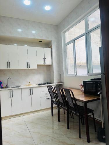 a kitchen with white cabinets and a wooden table and chairs at Nizami Hostel in Baku