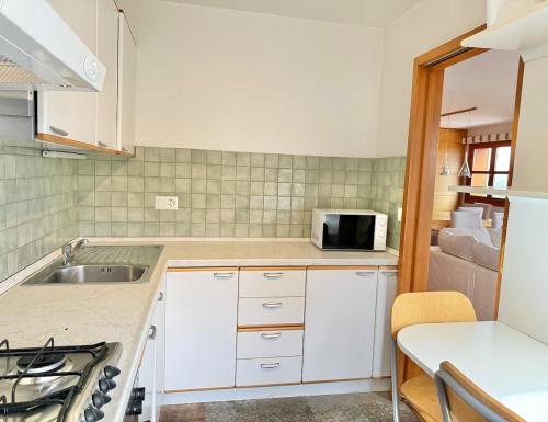 a kitchen with a sink and a microwave at Crans-Montana 3BR - Mountain View, Balcony and Parking in Crans-Montana