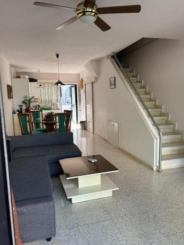 sala de estar con sofá azul y ventilador de techo en Two Floor Maisonette by the Sea, en Protaras