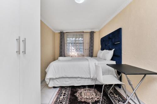 a bedroom with a large bed and a table at Private Garden Cottage with Kitchenette in Johannesburg