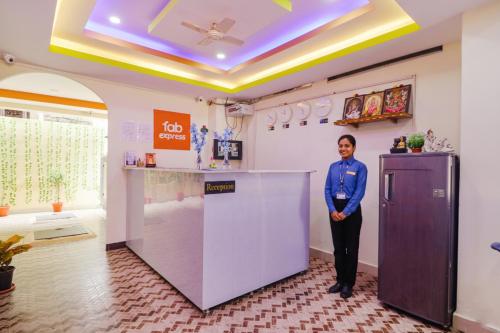 Una mujer parada detrás de un mostrador en una habitación. en FabExpress Broholic Suites - Nr JNTU Kukatpally, en Hyderabad