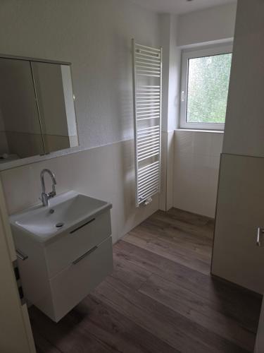 un bagno con un lavandino, uno specchio e una finestra di Haus Sonnenschein a Dornum