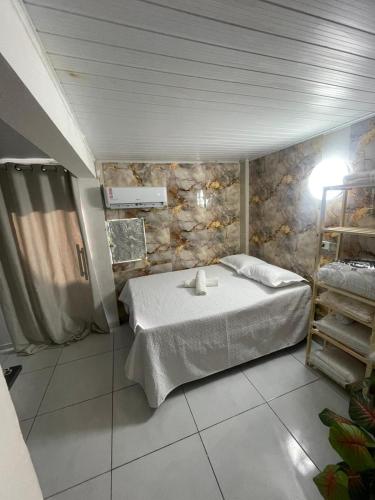 ein Schlafzimmer mit einem Bett und einer Steinwand in der Unterkunft Kit net morro de são Paulo in Cayru