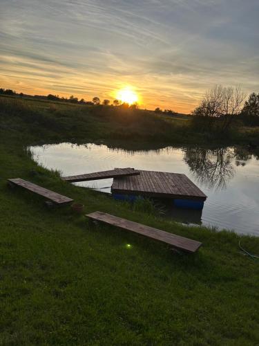 a river with a dock in the grass with the sunset at Pūnas in Cēsis