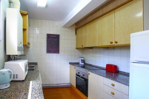 a small kitchen with a refrigerator and a sink at DELFINES Apartment in La Pineda