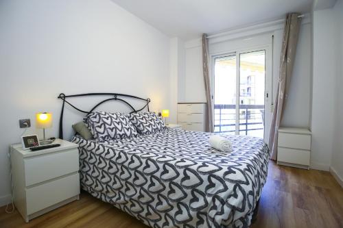 a bedroom with a bed with a black and white comforter at FORMENTOR Apartment in Salou