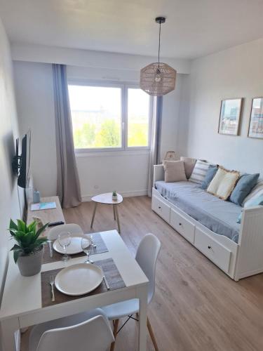 a living room with a couch and a table at L'escapade Sweet home - vue sur Mer et Dragon de Calais in Calais