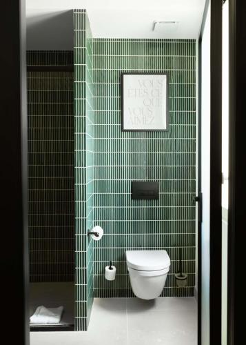 a green tiled bathroom with a toilet in it at Limehome Paris Montmartre in Paris