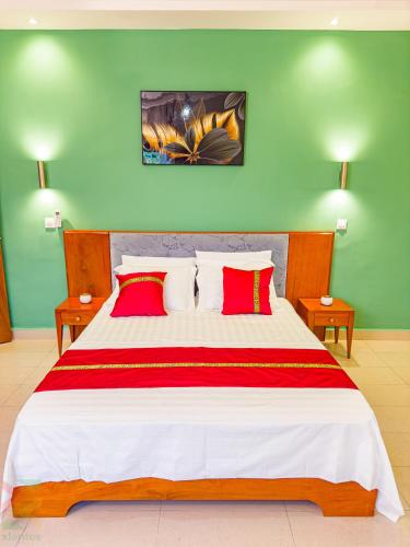 a bedroom with a large bed with red and white pillows at La Source, Kribi in Kribi