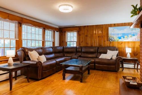 a living room with a leather couch and a table at Naples Village Retreat - Heart of the Lakes Region in Naples