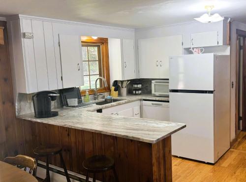 a kitchen with white cabinets and a white refrigerator at Naples Village Retreat - Heart of the Lakes Region in Naples