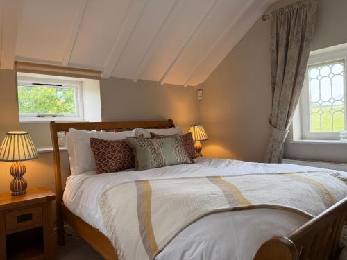 a bedroom with a large bed and two windows at North Lodge at Pudleston Court in Hatfield
