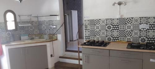 a kitchen with white cabinets and a black and white tile wall at Les Favouilles - Gîte & Chambres d hôtes in Dauphin