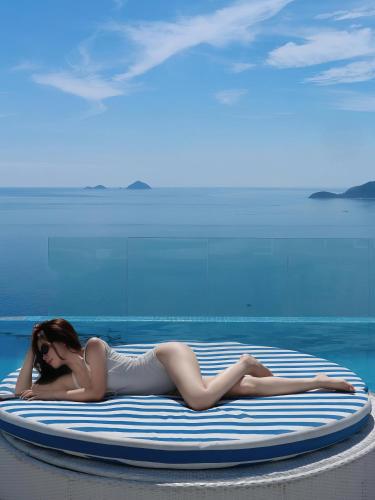 a woman in a bikini laying on a surfboard at VELA OCEAN LUXURY SUITES Nha Trang Centre in Nha Trang