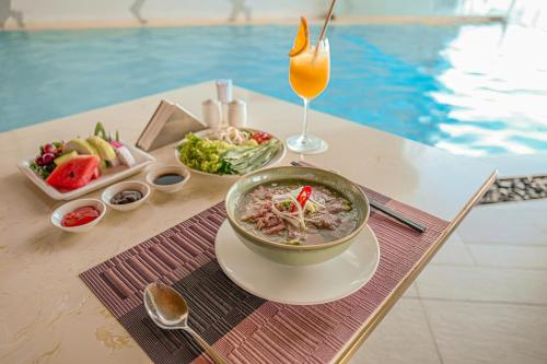 a table with a bowl of soup and a drink at VELA OCEAN LUXURY SUITES Nha Trang Centre in Nha Trang