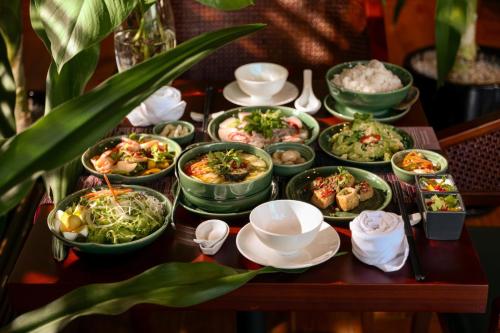 a table with many dishes of food on it at VELA OCEAN LUXURY SUITES Nha Trang Centre in Nha Trang