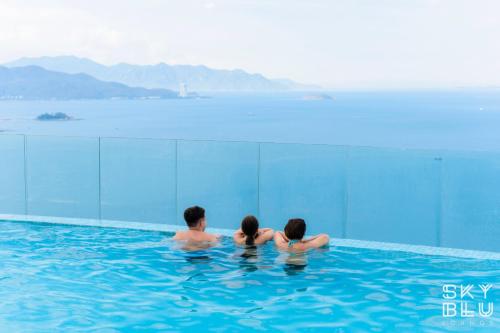a man and two women sitting in a swimming pool at Coastal Charm Panorama Bayview in Nha Trang