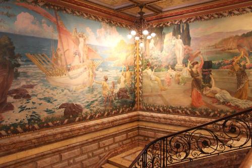 a large painting on the wall of a room with a staircase at ibis budget Perpignan Centre Rénové en 2025 in Perpignan