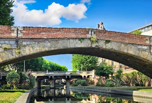 a bridge over a river with people walking on it at ibis budget Perpignan Centre Rénové en 2025 in Perpignan