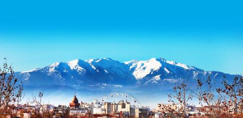 a city with snow capped mountains in the background at ibis budget Perpignan Centre Rénové en 2025 in Perpignan
