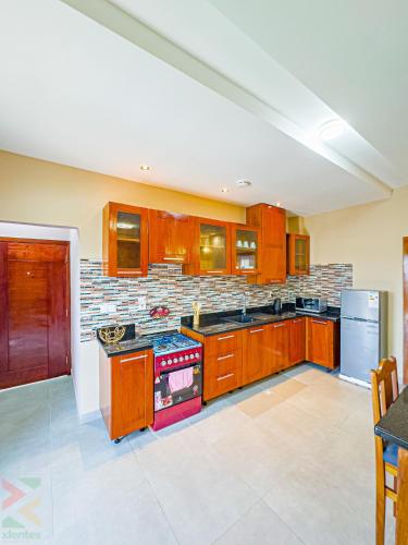a kitchen with wooden cabinets and a stove top oven at La Source, Kribi in Kribi
